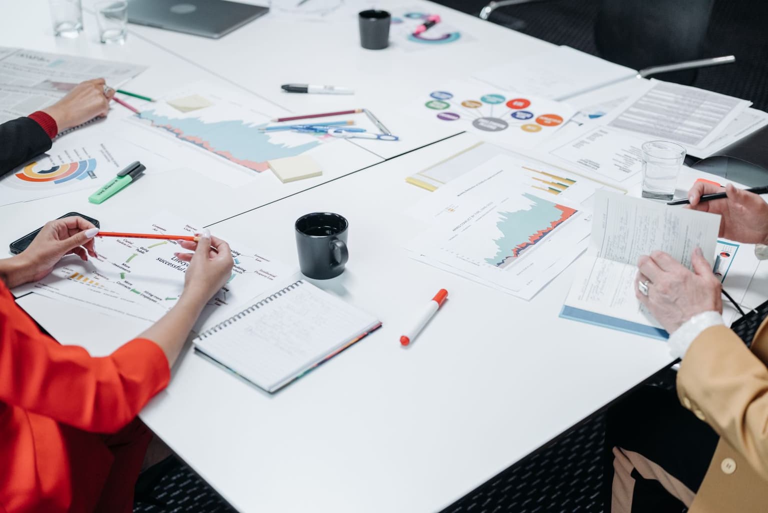 People comparing reports and notes around a table